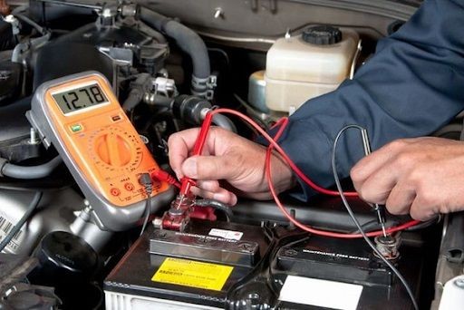 Kỹ thuật viên đang kiểm tra bình ắc quy xe ô tô, một công việc quan trọng để đánh giá thông số bình ắc quy
