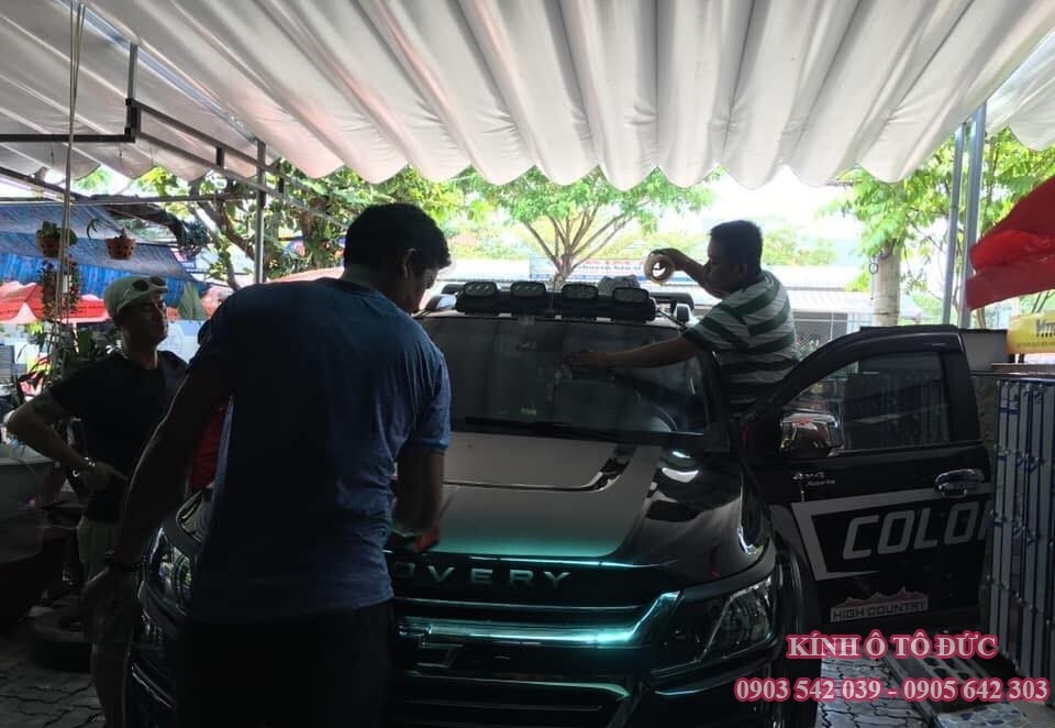Một công nhân đang thực hiện công việc trên kính chắn gió của ô tô