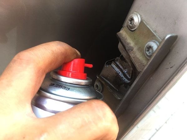 Hình ảnh xịt dung dịch bảo dưỡng vào ổ khóa cửa trượt xe ô tô 16 chỗ để đảm bảo hoạt động trơn tru