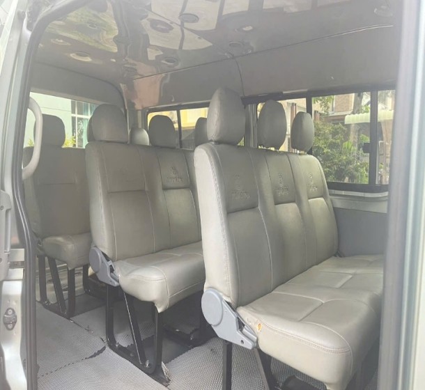 Phía sau của một xe ô tô cũ 16 chỗ Toyota Hiace màu trắng, hiển thị cửa cốp và đèn hậu.
