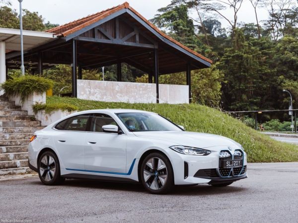 Xe sedan thể thao BMW i4 màu trắng đang di chuyển, biểu tượng cho khả năng điện hóa hoàn toàn của BMW, ảnh hưởng đến thiết kế của xe ô tô 7 chỗ BMW.