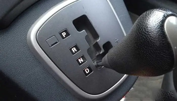 Bàn tay đang di chuyển cần số xe ô tô số tự động từ vị trí P (Park) sang D (Drive) để bắt đầu lái.