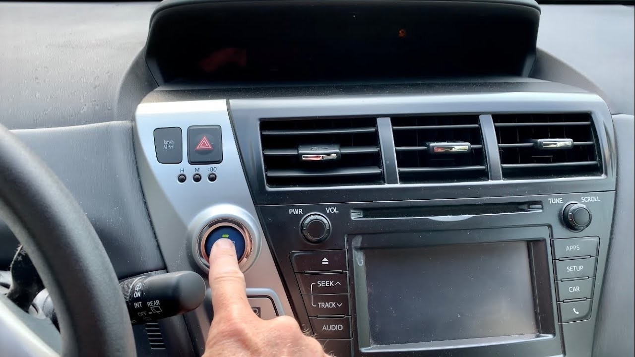 Bàn tay đang dùng ngón cái nhấn vào nút khởi động Engine Start Stop trên bảng điều khiển xe ô tô.