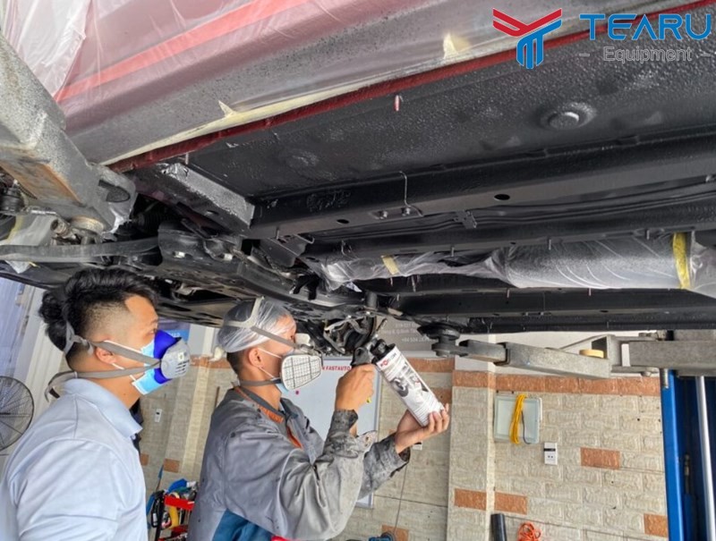 Kỹ thuật viên đang phun lớp phủ bảo vệ cho gầm xe ô tô chuyên nghiệp