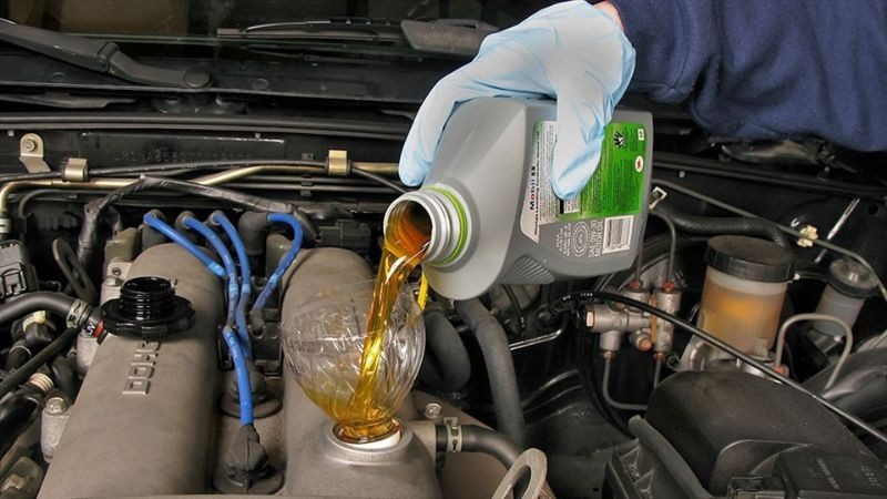 Đổ dầu nhớt mới vào động cơ xe ô tô tải qua phễu một cách cẩn thận