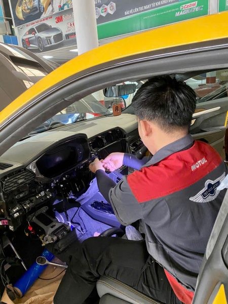 Kỹ thuật viên đang thực hiện sửa chữa hệ thống điều hòa trên xe ô tô