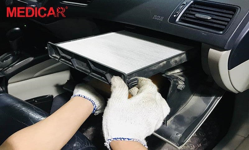 Thợ kỹ thuật đang tháo lọc gió điều hòa bị bám bẩn để vệ sinh, khắc phục mùi hôi xe ô tô