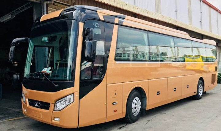 Xe khách màu đỏ đang di chuyển, ảnh hưởng đến tiêu hao nhiên liệu các loại xe ô tô khách tùy thuộc vào số lượng hành khách.