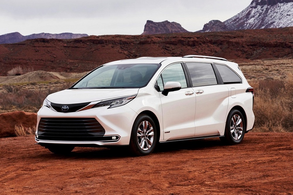 Hình ảnh một chiếc mini van màu trắng bạc đang đỗ bên đường, với thiết kế thân xe lớn, cửa lùa và không gian nội thất rộng rãi