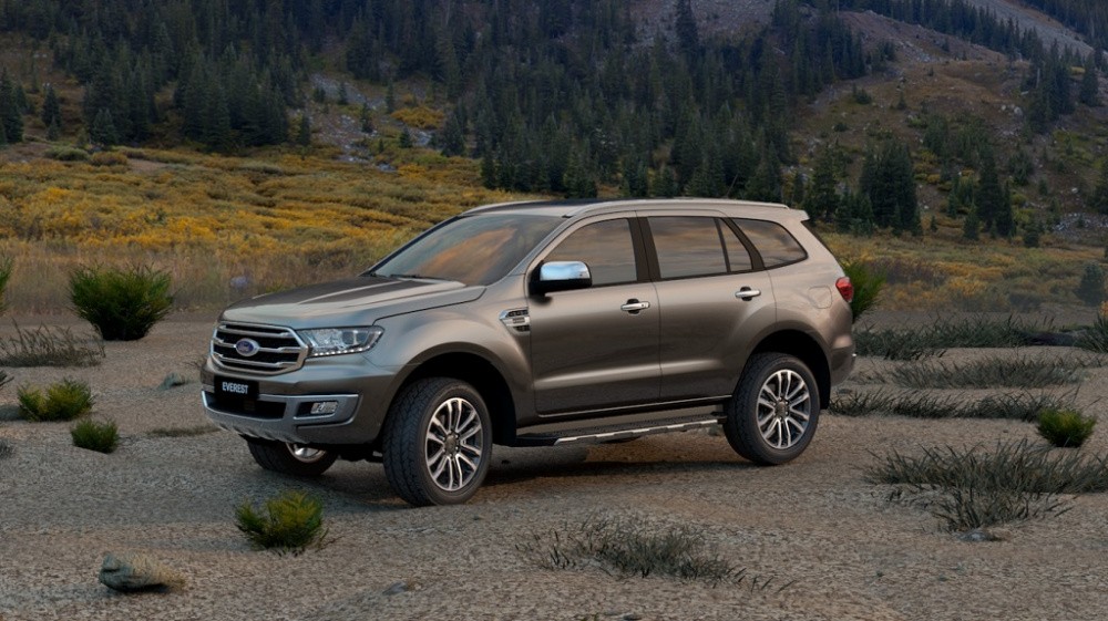 Hình ảnh một chiếc SUV màu trắng bạc đang di chuyển trên đường đất, nhấn mạnh đặc trưng gầm cao và khả năng vận hành địa hình