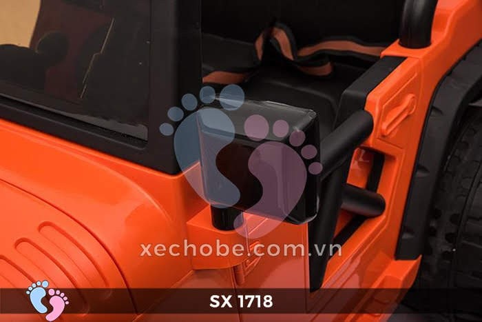 Bé gái ngồi trên xe ô tô điện trẻ em SX 1718 màu đỏ, tay cầm vô lăng và chuẩn bị lái