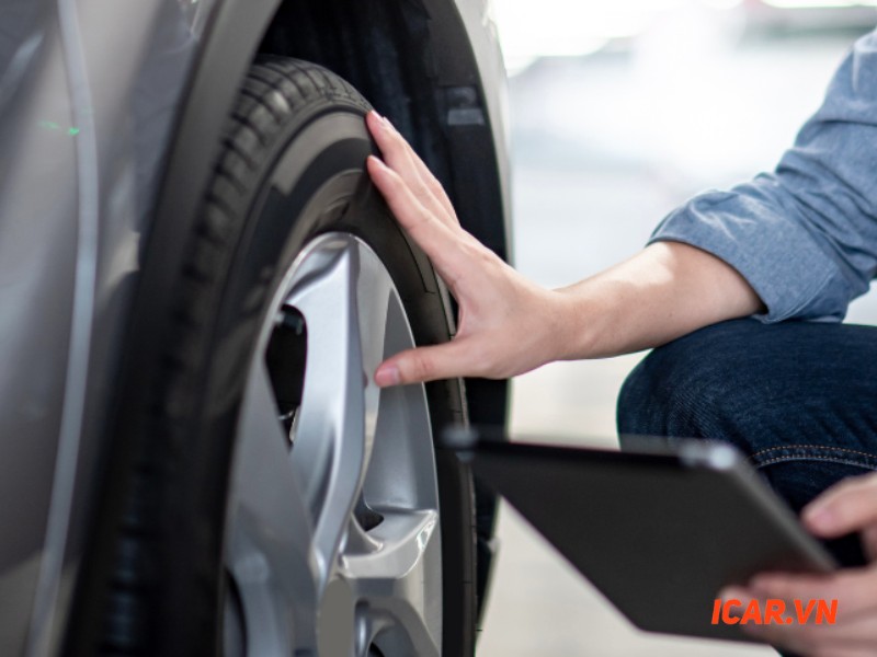 Kỹ thuật viên đang kiểm tra lốp và bánh xe, một phần quan trọng trong kinh nghiệm mua xe ô tô cũ.