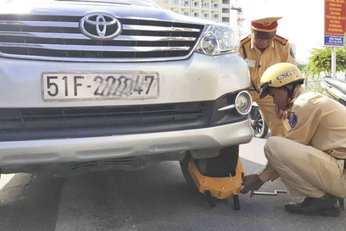 Hình ảnh lực lượng chức năng Nha Trang sử dụng cùm bánh xe ô tô để xử lý phương tiện đỗ sai quy định, góp phần ổn định trật tự giao thông đô thị.