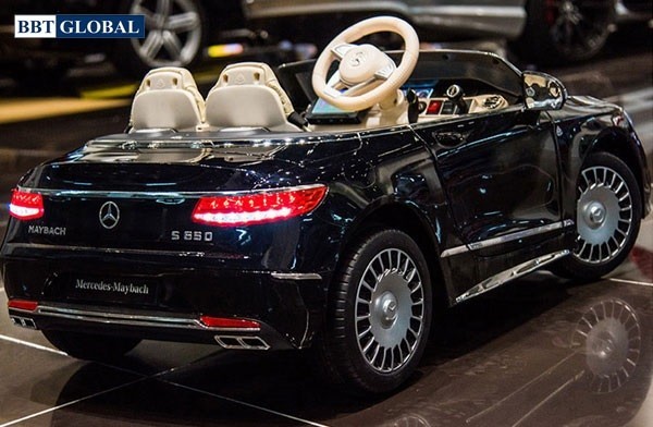 Một bé gái đang vui chơi bên chiếc xe ô tô điện trẻ em Mercedes Maybach S650