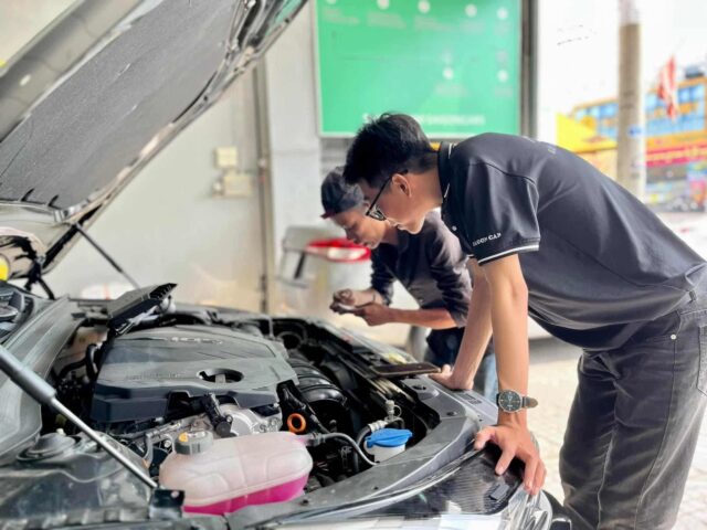 Chuyên gia đang kiểm tra động cơ xe ô tô cũ để xác định giá trị và thuế giá trị gia tăng xe ô tô