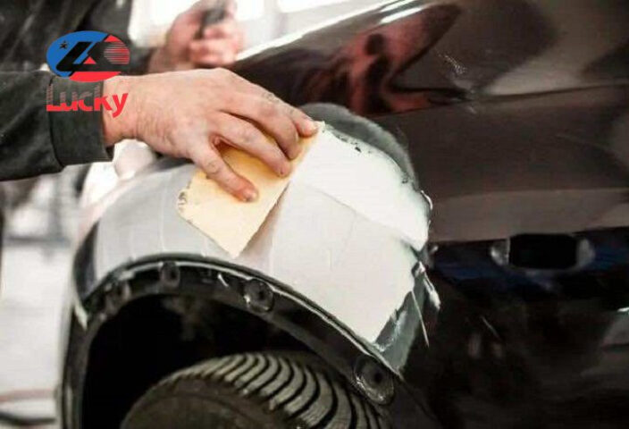 Chuyên viên đang bả matit vỏ xe ô tô để làm phẳng bề mặt