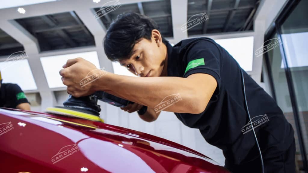 Người thợ đang thực hiện công đoạn đánh bóng trên thân xe ô tô màu đỏ