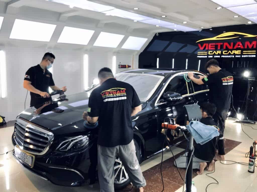 Ba kỹ thuật viên đang chăm sóc chiếc xe ô tô màu đen trong xưởng