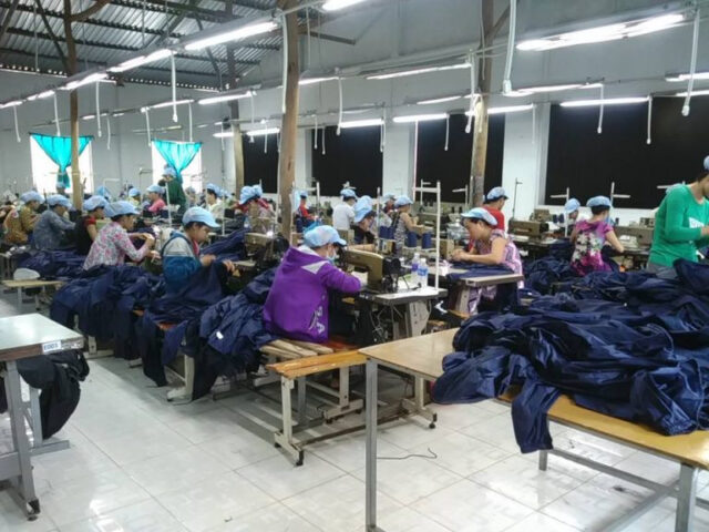 Công nhân kiểm tra chất lượng sản phẩm bạt phủ máy xe ô tô trong quá trình sản xuất.