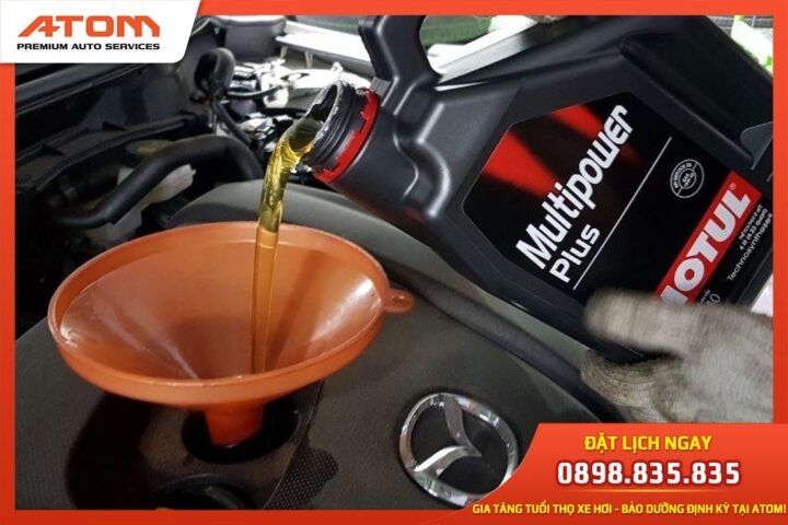 Kỹ thuật viên đang đổ dầu nhớt mới vào động cơ xe ô tô máy dầu trong quá trình bảo dưỡng định kỳ