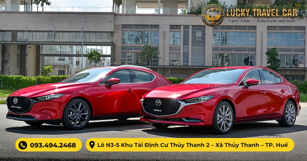 Mazda 3 màu đỏ đang đỗ trên con đường rợp bóng cây, phía sau là hàng rào