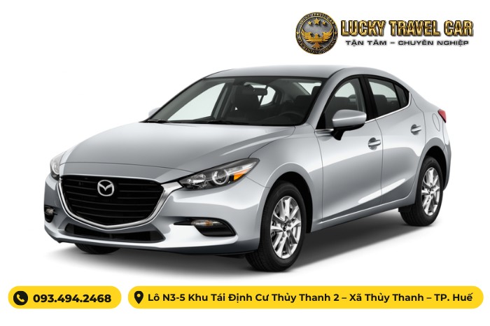 Mazda 3 trắng đang đỗ trên đường phố với kiến trúc hiện đại
