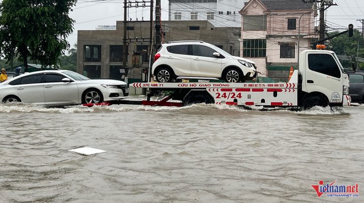 Dịch vụ ô tô cứu hộ xe máy đang kéo hai xe hơi bị chết máy do ngập nước
