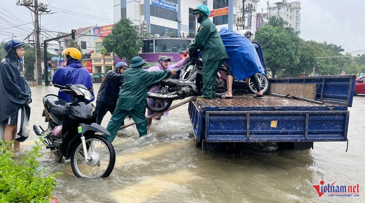 Dân quân hỗ trợ người dân cứu hộ xe máy khỏi vùng ngập lụt ở TP Vinh