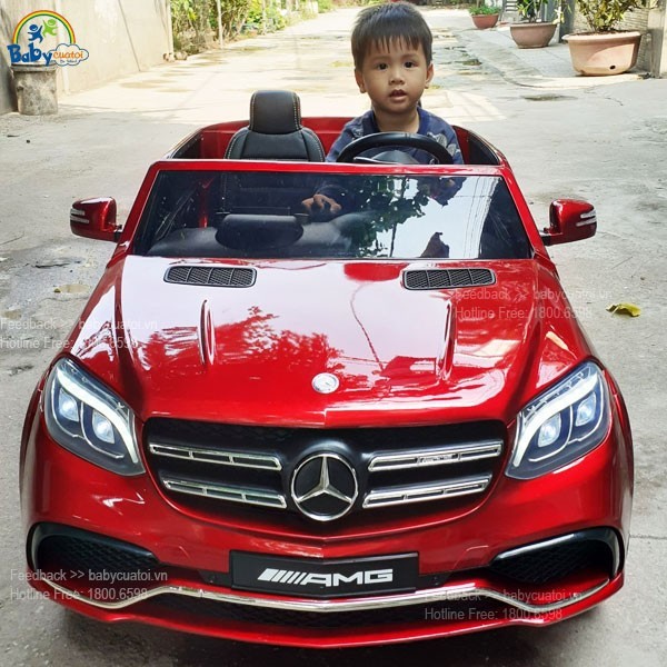 Bé gái tạo dáng bên chiếc xe ô tô điện trẻ em Mercedes AMG màu đỏ sang trọng.