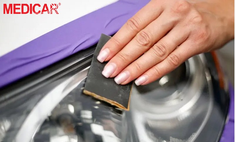 Đèn xe ô tô được đánh bóng bằng giấy nhám dưới vòi nước