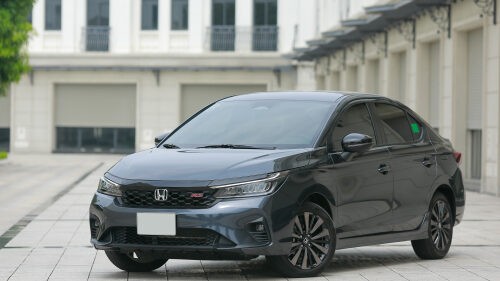 Hình ảnh xe Honda City màu đỏ tươi đang di chuyển trên đường, nổi bật với thiết kế thể thao và hiện đại, minh họa cho một mẫu xe ô tô tầm trung phổ biến.
