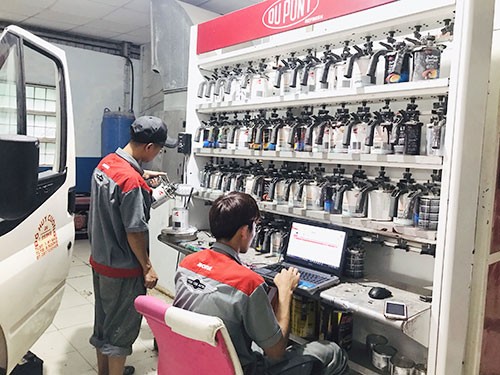Kỹ thuật viên đang kiểm tra và pha màu sơn xe ô tô bằng hệ thống máy tính tại TPHCM