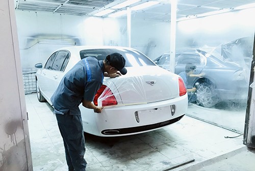 Kỹ thuật viên có kinh nghiệm đang thực hiện công đoạn sơn xe ô tô chuyên nghiệp tại TPHCM