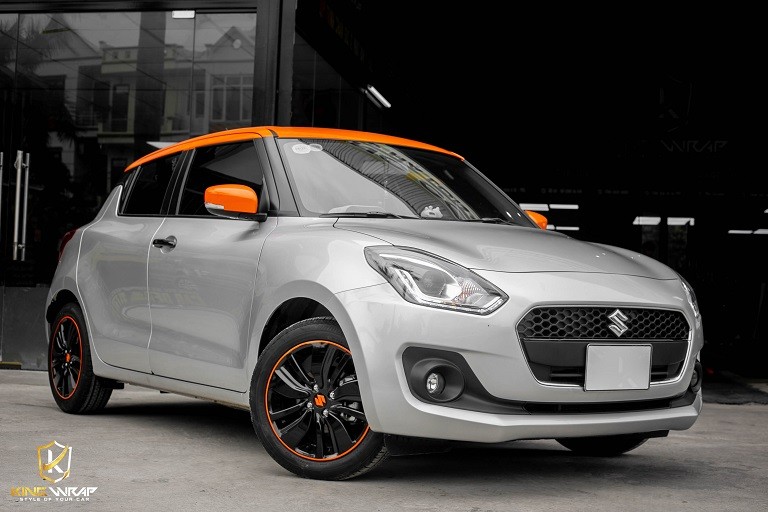 Suzuki Swift với decal tem xe ô tô màu cam nổi bật trên nền bạc, thể hiện sự cuốn hút và cá tính sau khi dán xe ô tô Suzuki Swift