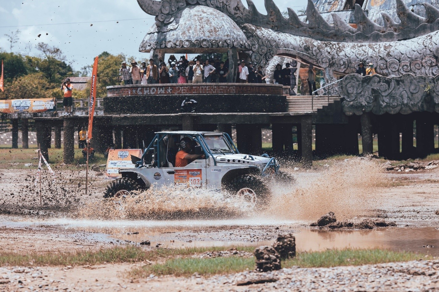 Một tay đua nữ tự tin điều khiển xe off-road trên đường đua bùn lầy, thể hiện kỹ năng lái xe vượt trội