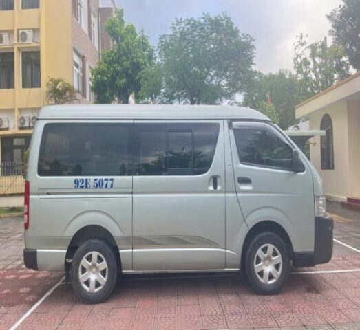 Xe ô tô cũ 16 chỗ Toyota Hiace màu trắng nhìn từ góc trước bên phải, minh họa tình trạng thân vỏ