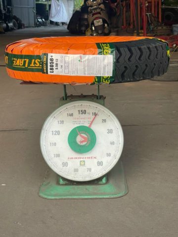 Người thợ đang cân trọng lượng lốp xe ô tô để xác định khối lượng chính xác