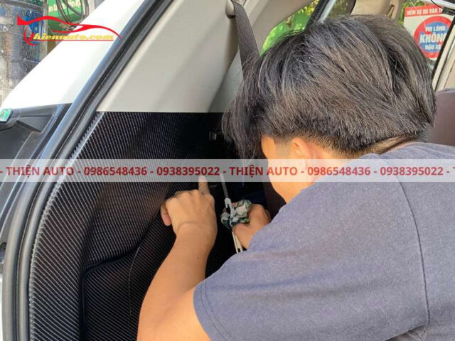 Thợ kỹ thuật chuyên nghiệp đang dán carbon nội thất xe ô tô tại vị trí thành cốp sau