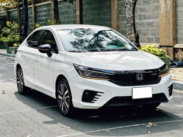 Xe ô tô Honda City cũ màu đỏ đang di chuyển trên đường phố