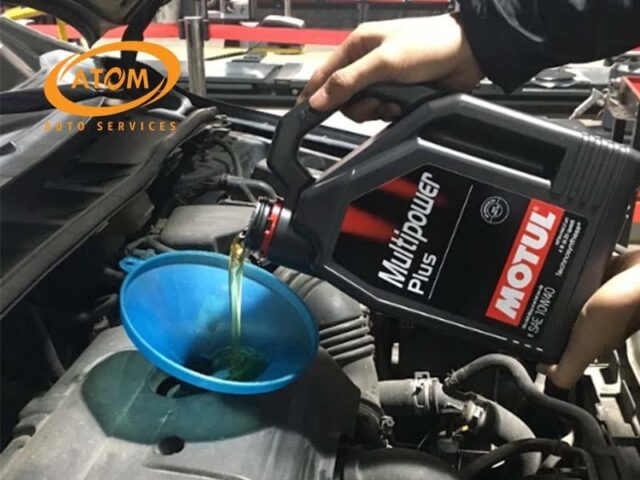 Kỹ thuật viên đang thực hiện thay dầu động cơ cho một chiếc xe ô tô mới, một bước quan trọng trong cách bảo dưỡng xe ô tô mới