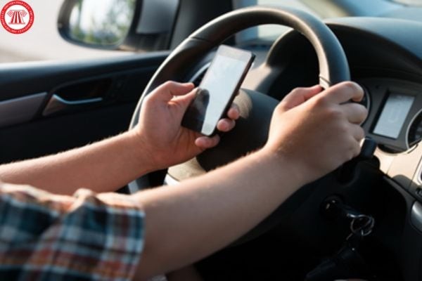 Hình ảnh người lái xe ô tô dùng điện thoại khi xe ô tô chạy trên đường, minh họa hành vi vi phạm giao thông.