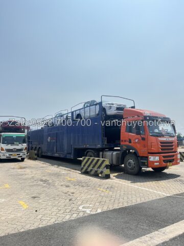 Xe ô tô đang được vận chuyển trên xe lồng chuyên dụng, thể hiện quy trình vận chuyển an toàn và các yếu tố ảnh hưởng đến chi phí vận chuyển xe ô tô.